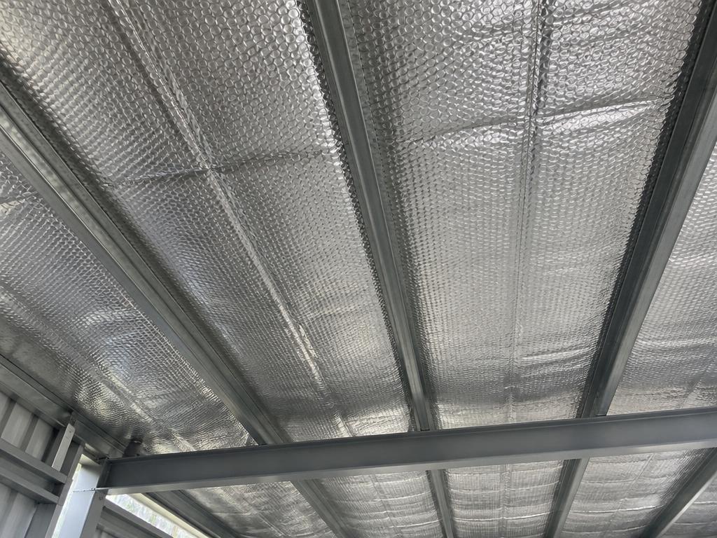 Double-bubble reflective foil insulation installed across steel roof purlins in a metal building
